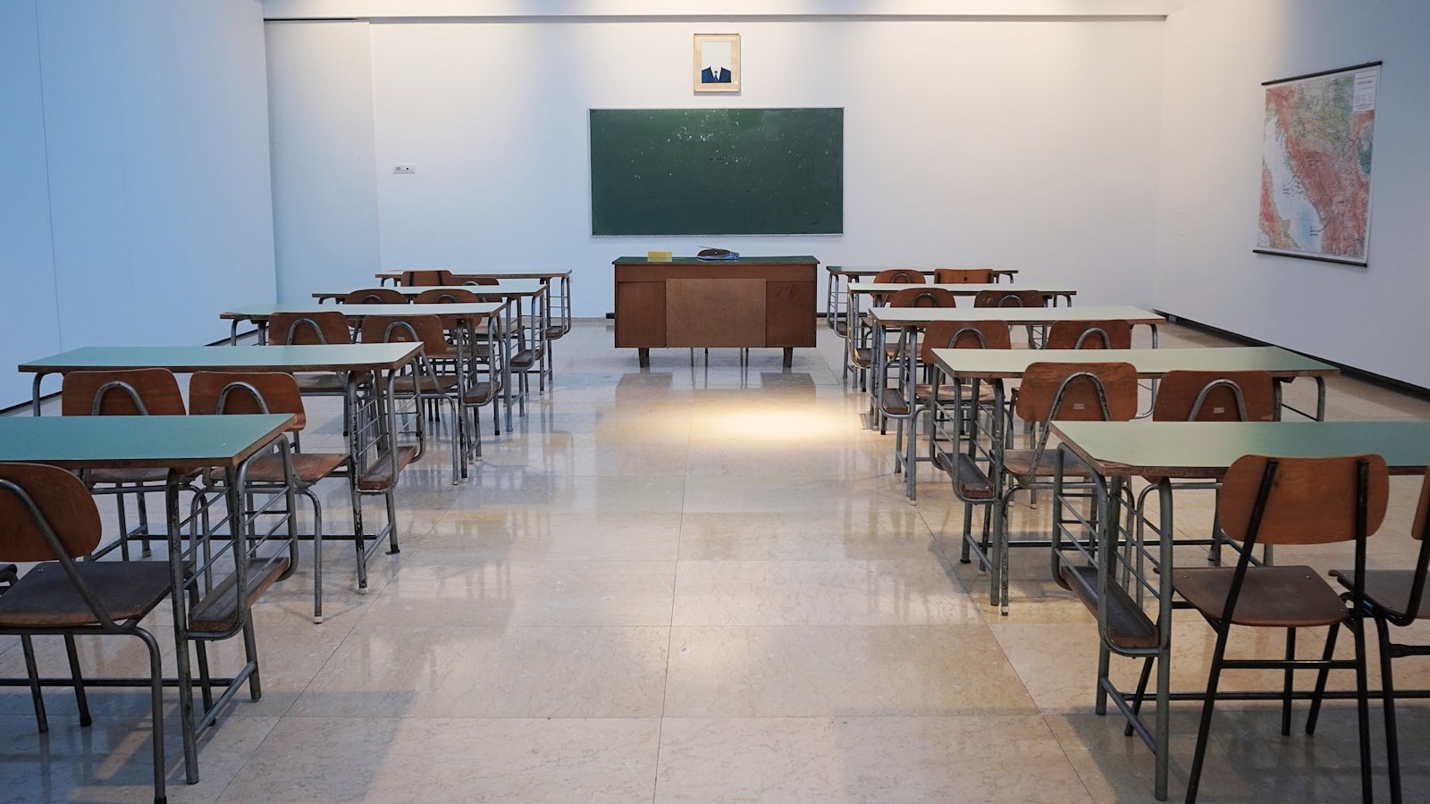 An empty classroom with rows of desks facing a chalkboard.