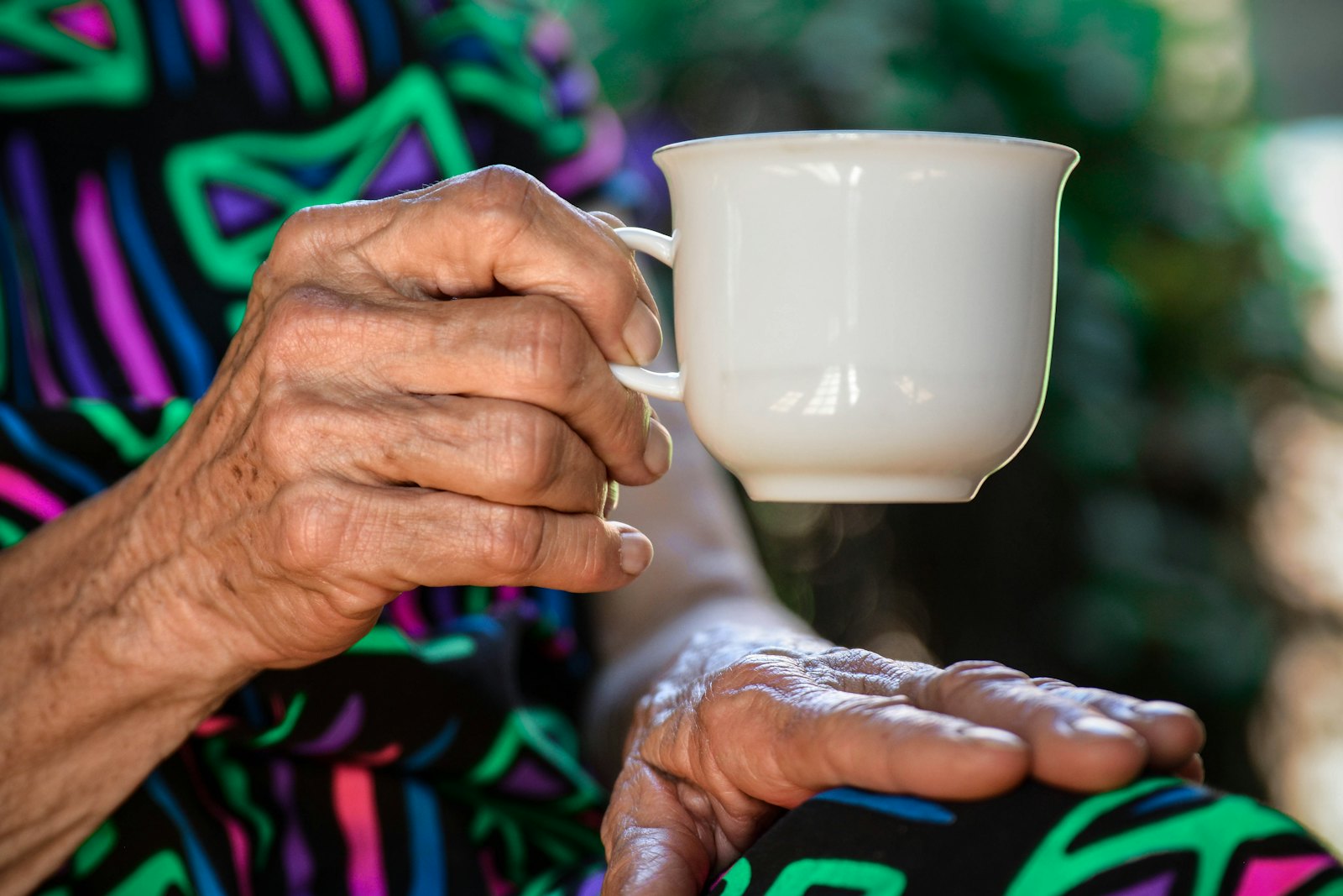 The hands of an older person holding a cup of tea.