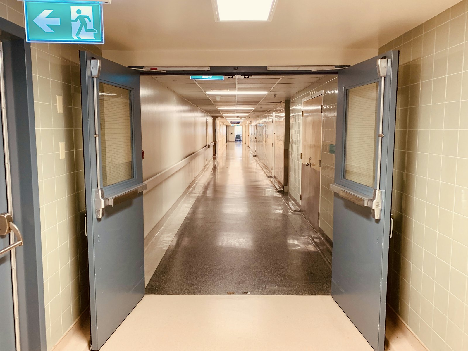 An empty hospital corridor lined with patient-room doors.